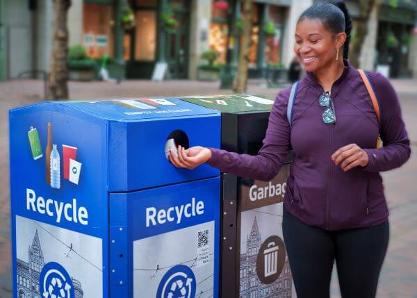 Smiling woman dropping an item in a recycling can