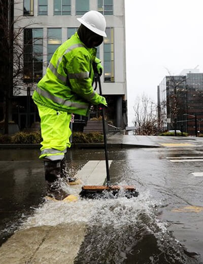 SPU employee sweeping water on a downtown street