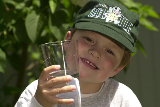 Smiling child holding a glass of drinking water