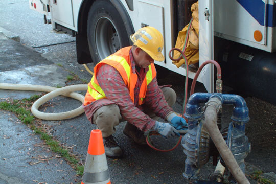 Water crewperson working with a pump beside a SPU truck.