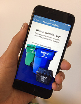 Photo of hand holding mobile device with Recycle It App on screen