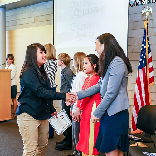 New American citizen shaking hands with Deputy Mayor Hyeok Kim at a past Citizenship Ceremony at Seattle City Hall.