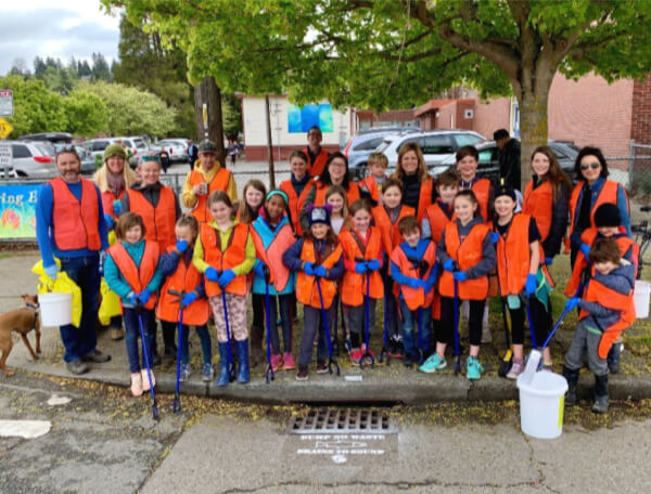 Photo of a group of volunteers of various ages standing on a street corner wearing orange vests.