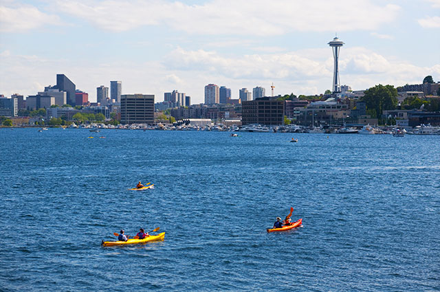 Kayaks on Lake Union on a sunny day with downtown Seattle in background.