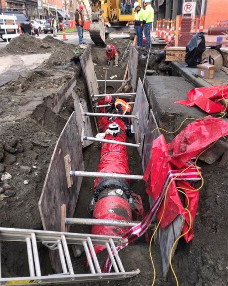 Photo of a seismically resistant pipe installation in a trench in Pioneer Square, with workesr in background