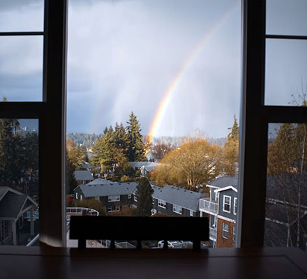 A rainbow is seen through a window over a Seattle neighborhood