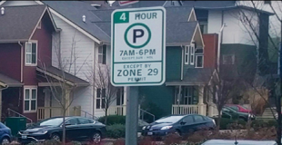 Parking sign in front of houses and cars