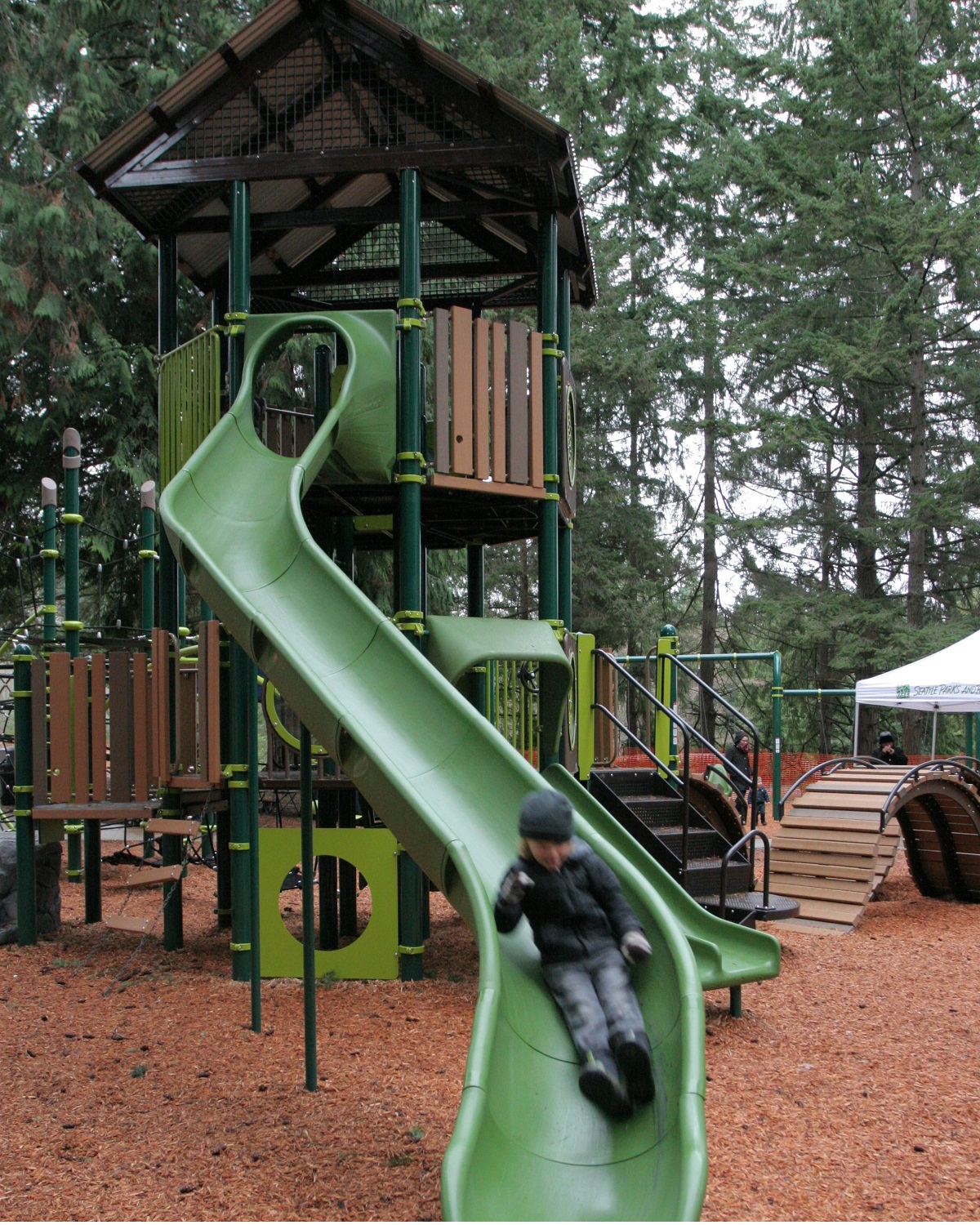 Youngster sliding down long green slide at new play area