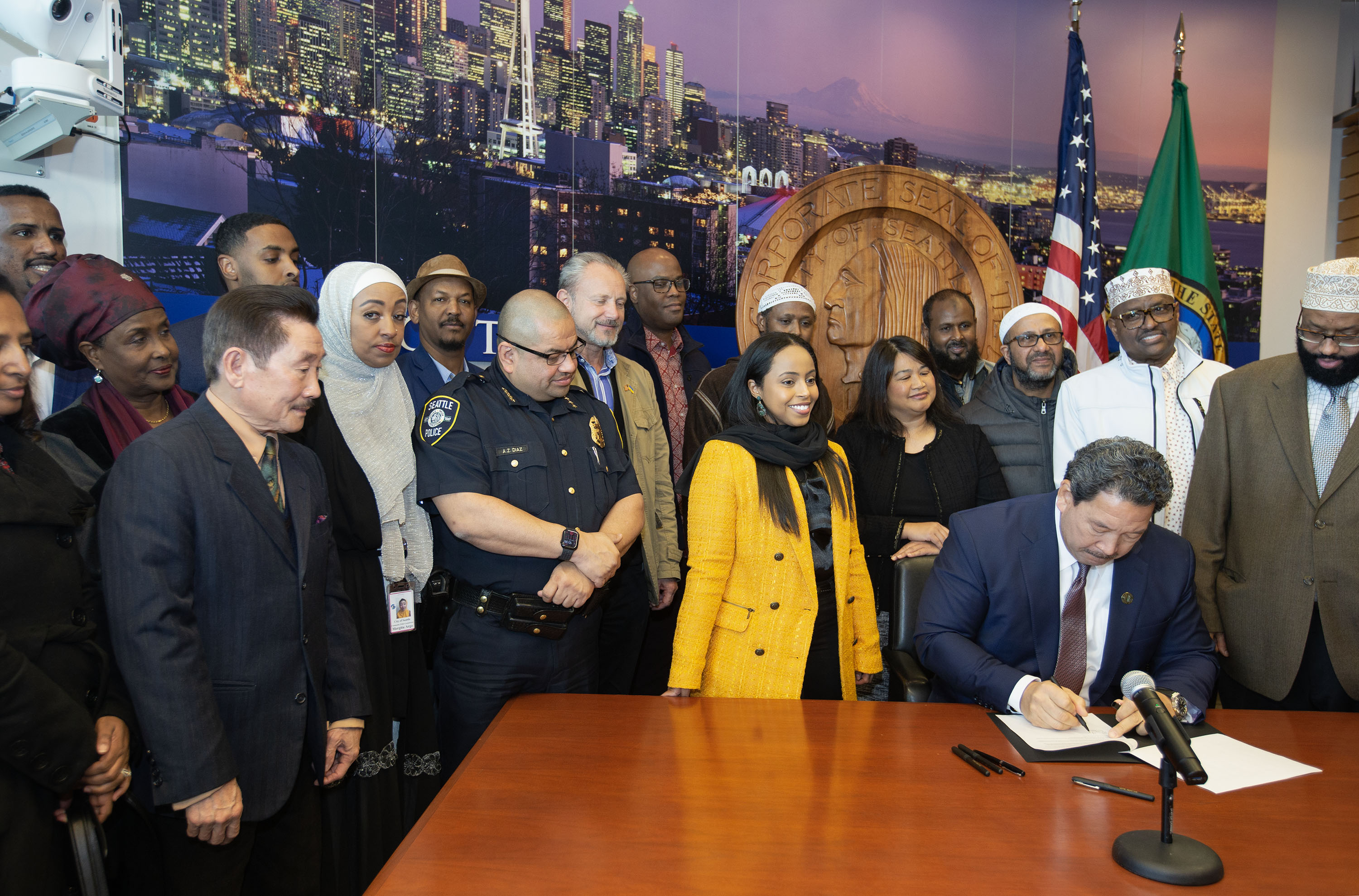 Mayor Bruce Harrell signing a bill in front of a group of community members
