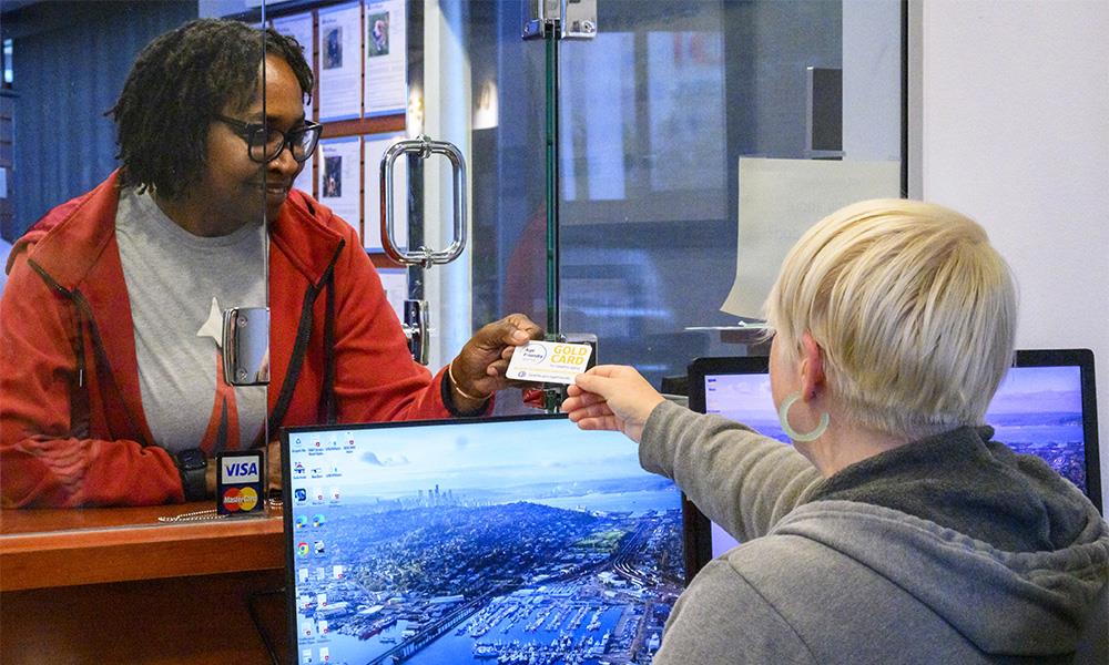 A woman presenting her Age Friendly Gold Card to receive a discount at a business.