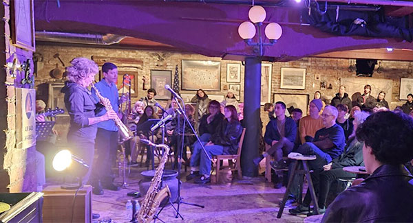 A jazz trio plays in front of a full audience