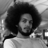 Black and white photo of a Black man with an afro and beard