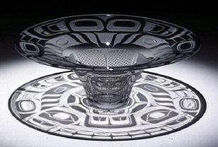 A glass artwork in the shape of a hat resting upside down featuring Northwest Coast Native designs