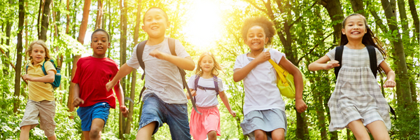 Children wearing backpacks run outside.