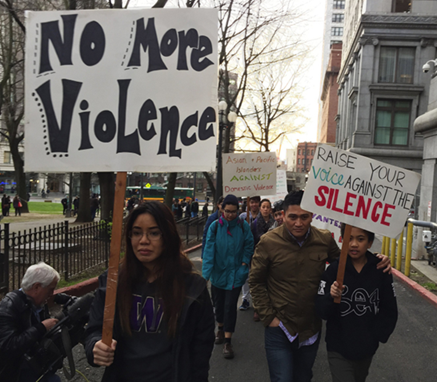 Women march outside the King County courthouse with protest signs demanding an end to domestic violence