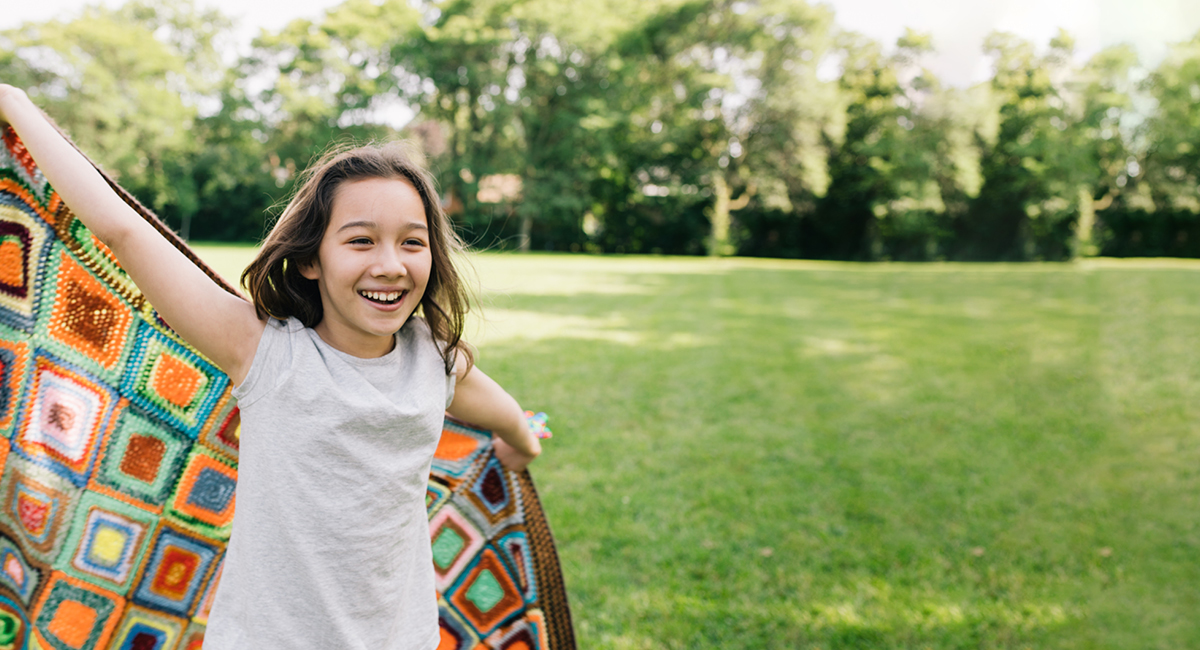 Smiling girl holding a colorful blanket outdoors