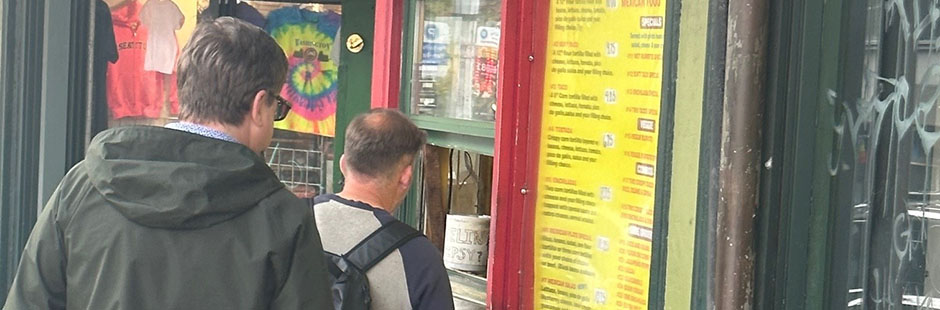 People lined up at a restaurant order window along the sidewalk.