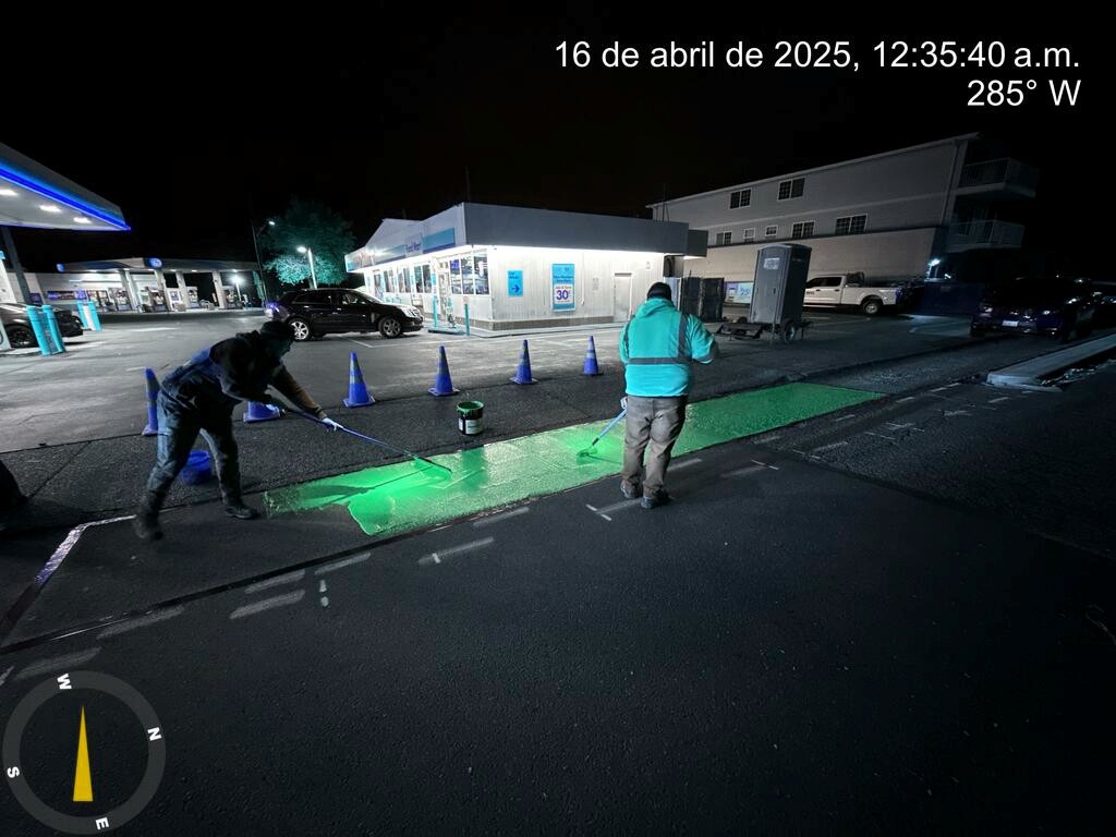 Crews installing green pavement markings in front of a driveway near 15th Ave S and S Bayview St