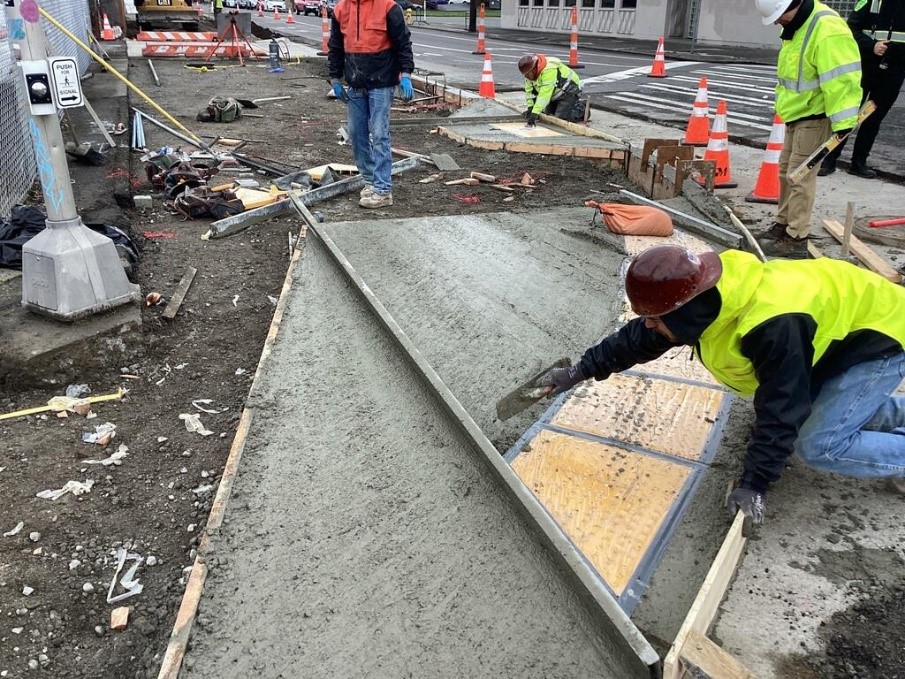 Crews constructing ADA-compliant curb ramps at northwest corner of 13th Ave S and S Albro Pl.