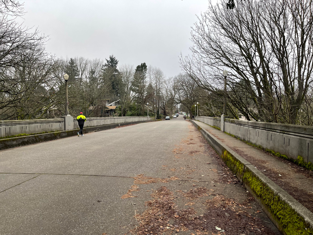 Photo of the existing McGraw St Bridge with a person wearing a bright reflective jacket running on the bridge. 