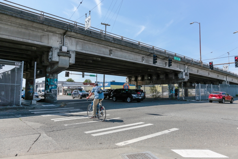 People biking and driving along Leary Way with the Leary Way Bridge above them