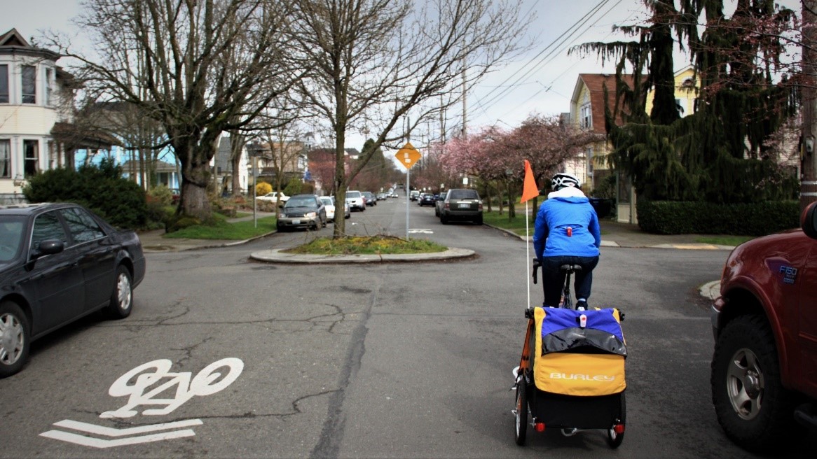 A cyclist riding with a trailer on a neighborhood greenway.