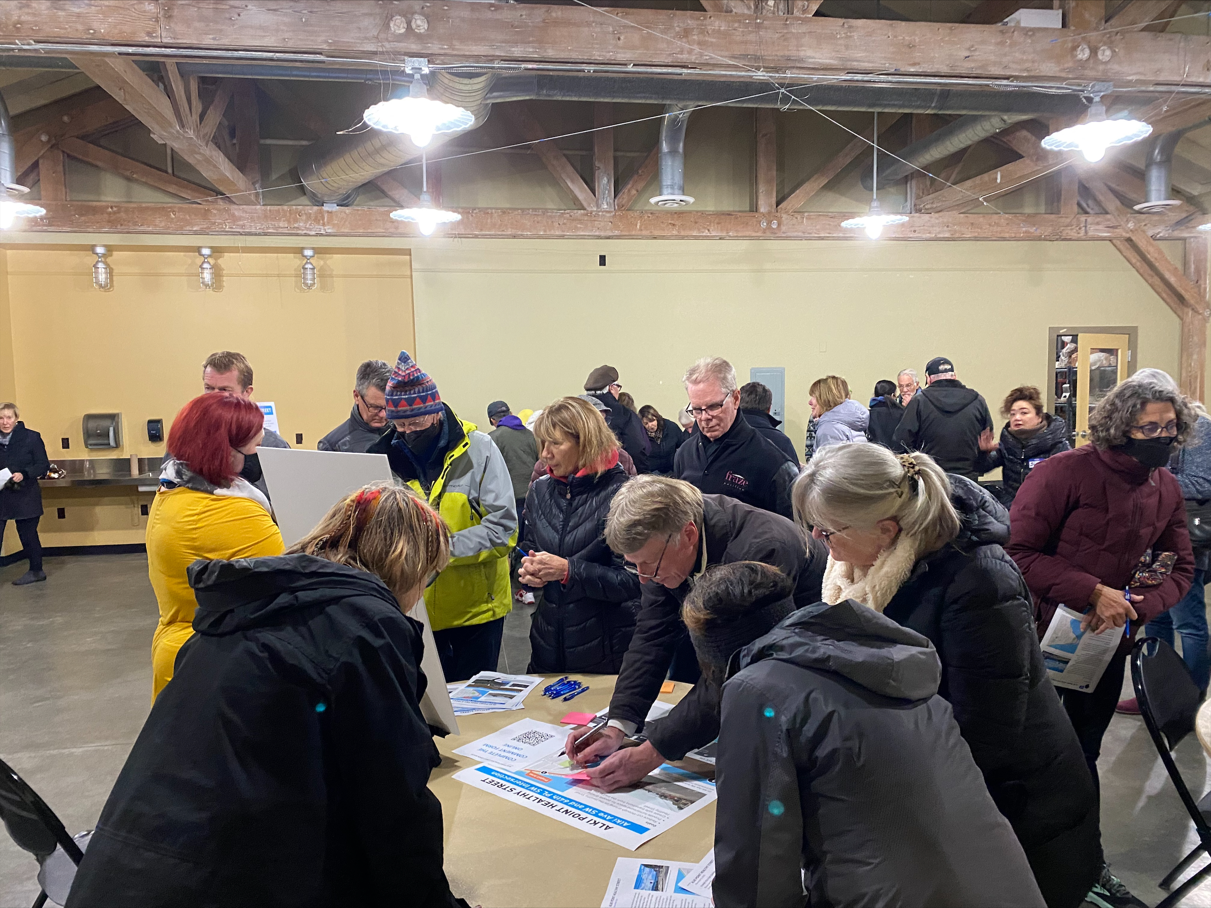 People gather at an open house and view proposed designs and materials on tables