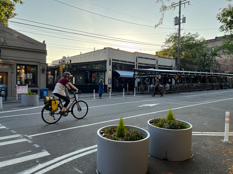 Cyclist riding down Ballard Ave next to newly installed planters