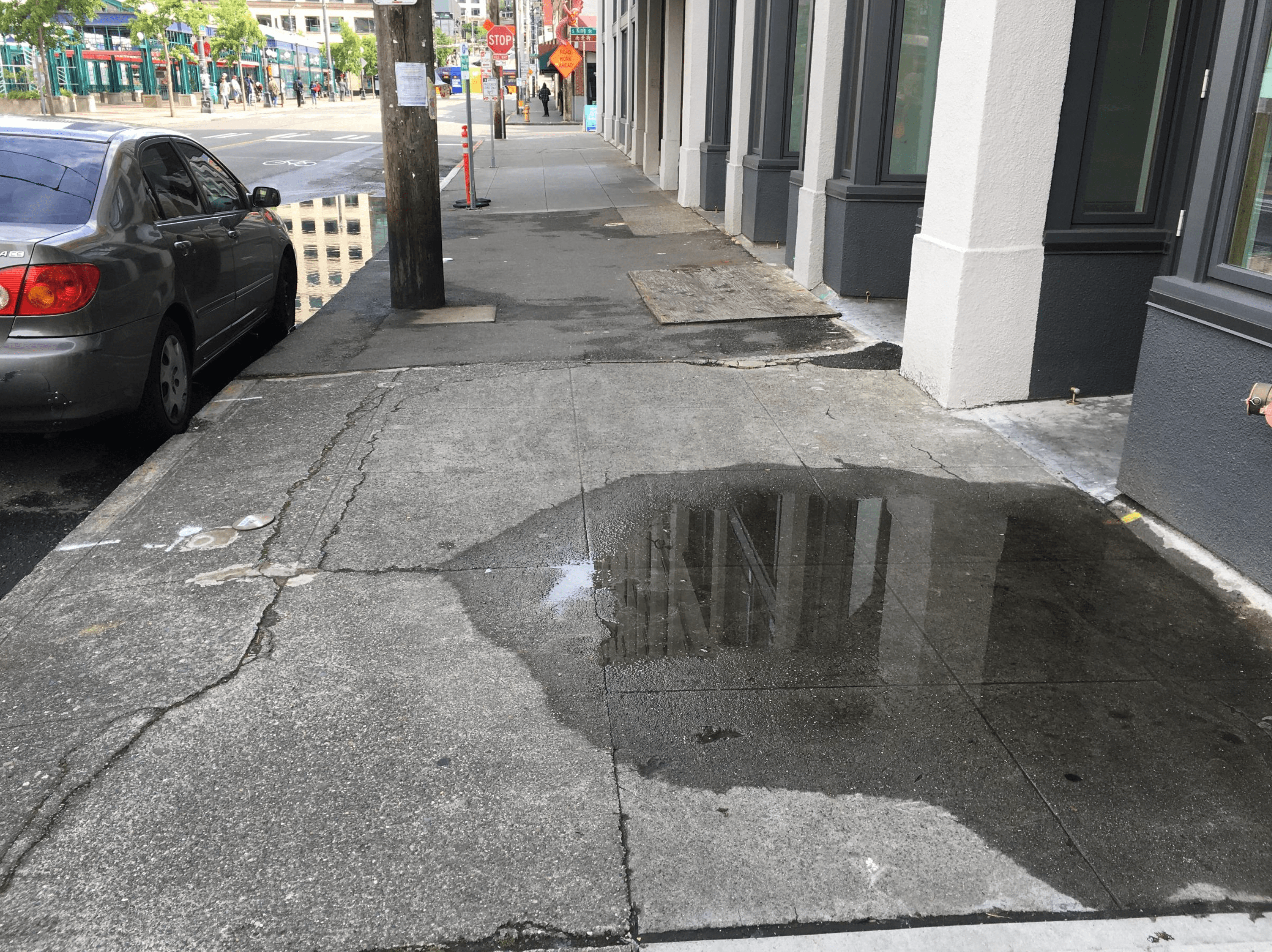 Acera con pendiente transversal aislada que causa que el agua se estanque.