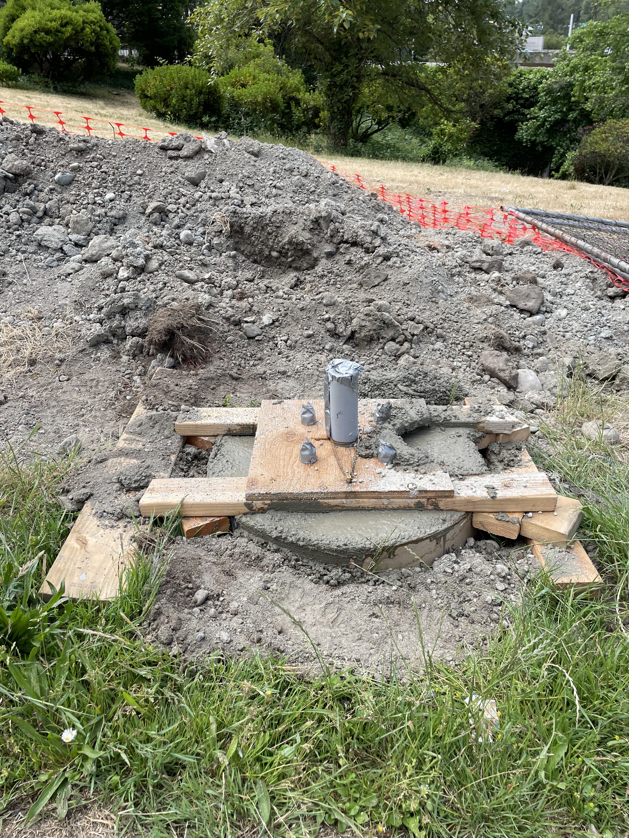 A metal post for the new trail lighting, set in concrete with wood framing