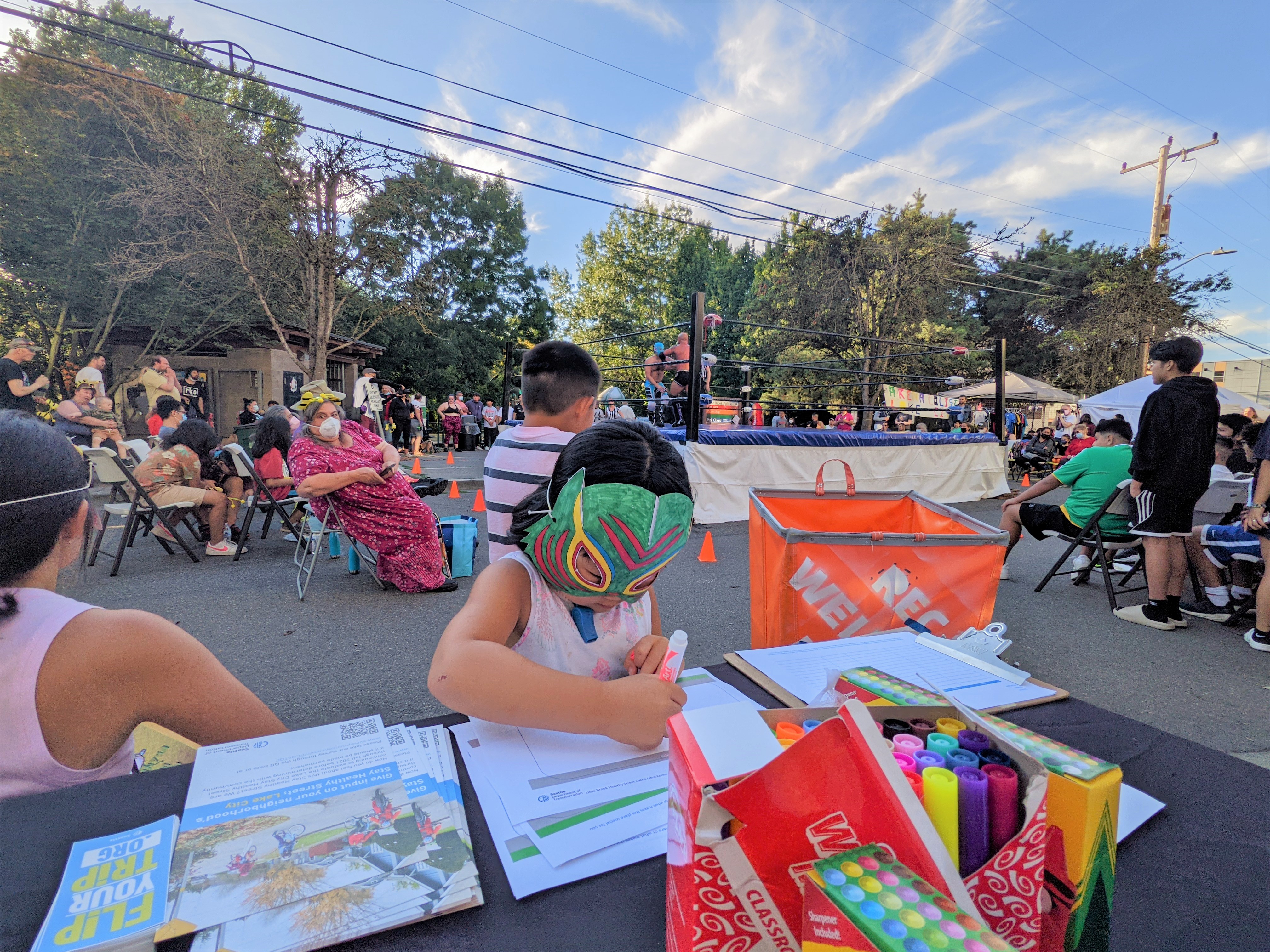 A child in a handmade Lucha Libre mask does arts and crafts at Little Brook's Healthy Street community event
