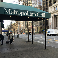 A green awning with the name Metropolitan Grill in white along the side,