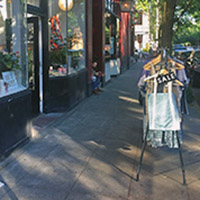 A rack of clothing on the sidewalk outside of a store.