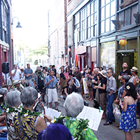 A large gathering of people in Canton Alley listening to a speaker.