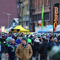 Sports fans outside of the stadium with vendors selling food and other merchandise to passersby.