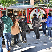 Multiple people waiting for their orders from a food truck
