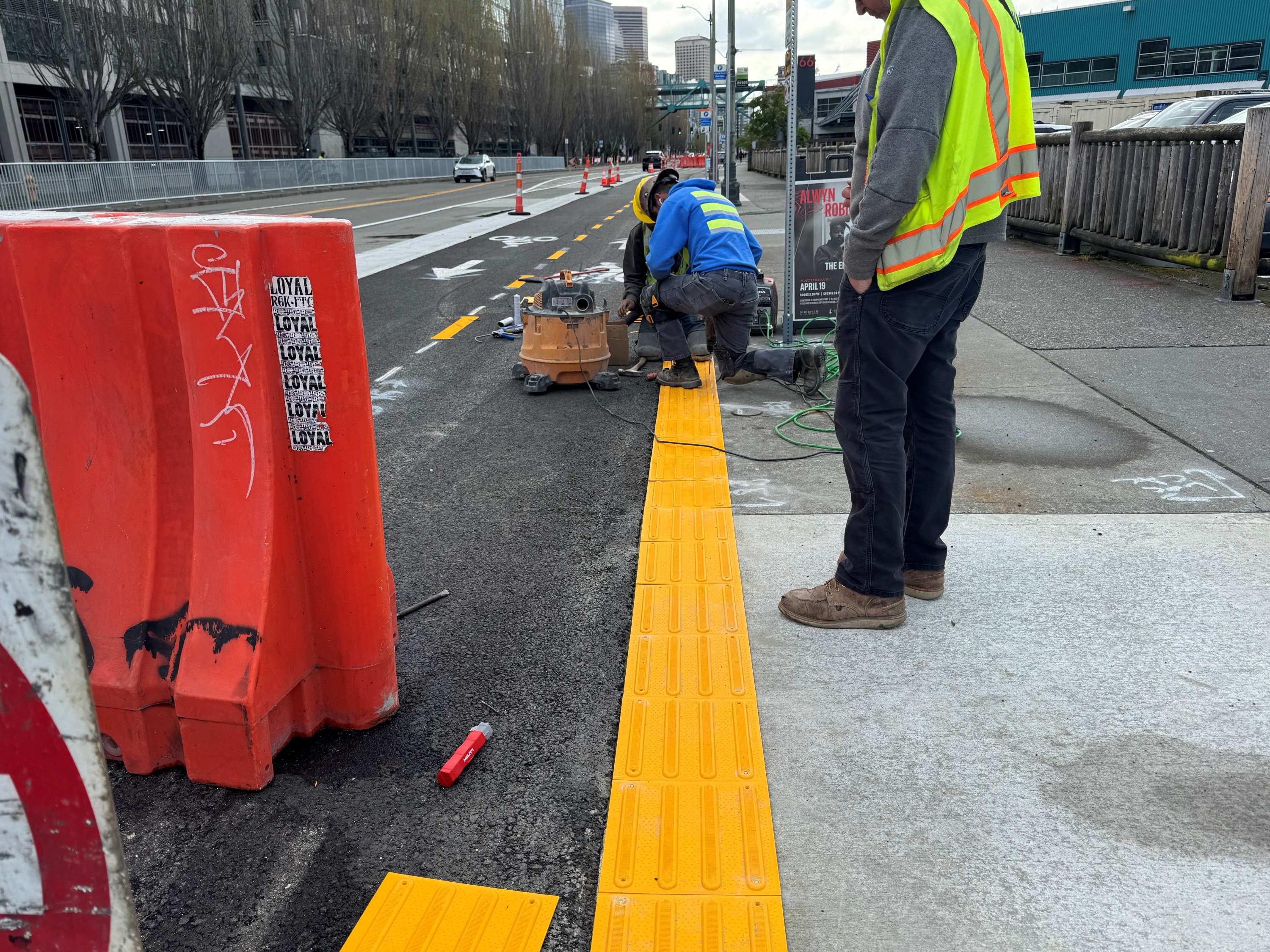 Crews installing detectable warning strip along curb on the west side of Alaskan Way.