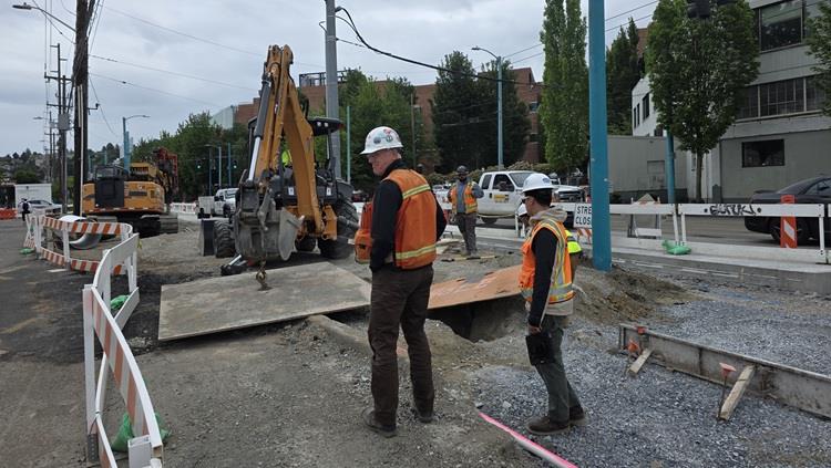 Image shows the construction zone on Fairview Ave N. In the image there are construction workers discussing the best approach to complete concrete pouring operations 