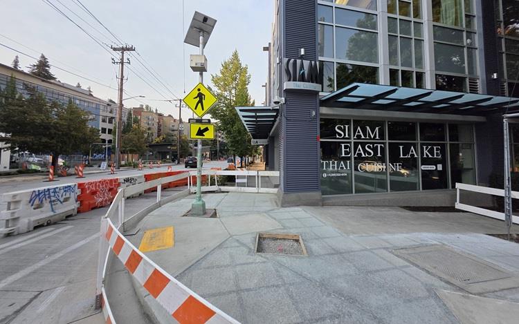 Image shows a large section of new sidewalk and pedestrian ramps recently completed along Eastlake Ave E