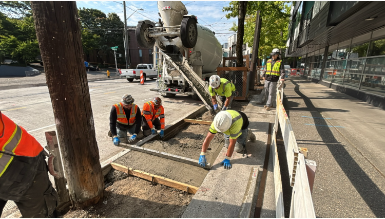 Image shows crews smoothing out concrete for sidewalks near Eastlake Ave E and E Hamlin St.