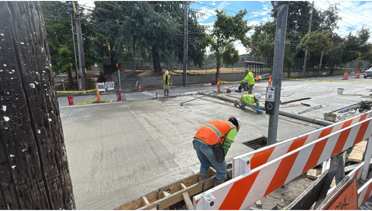 Image shows crews pouring new concrete on the west side of Eastlake Ave E and E Roanoke St.