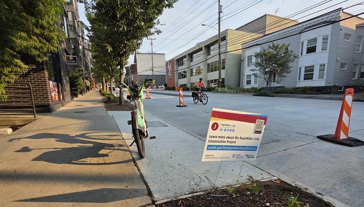 Image shows a cyclist biking beside an area of work on Eastlake Ave E