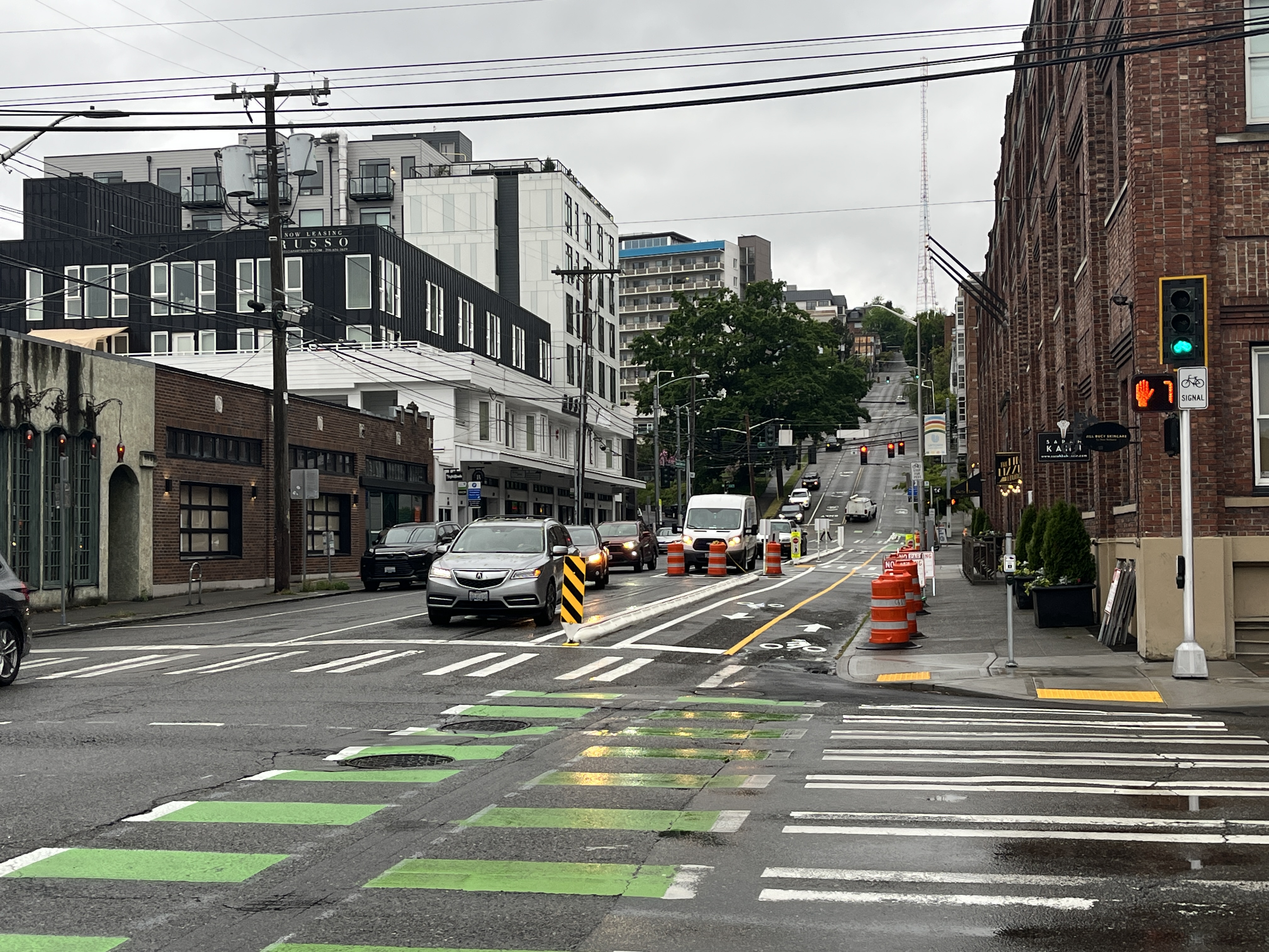 Street view looking north along Queen Anne Ave N, showing a new two-way protected bike lane with buildings on both sides
