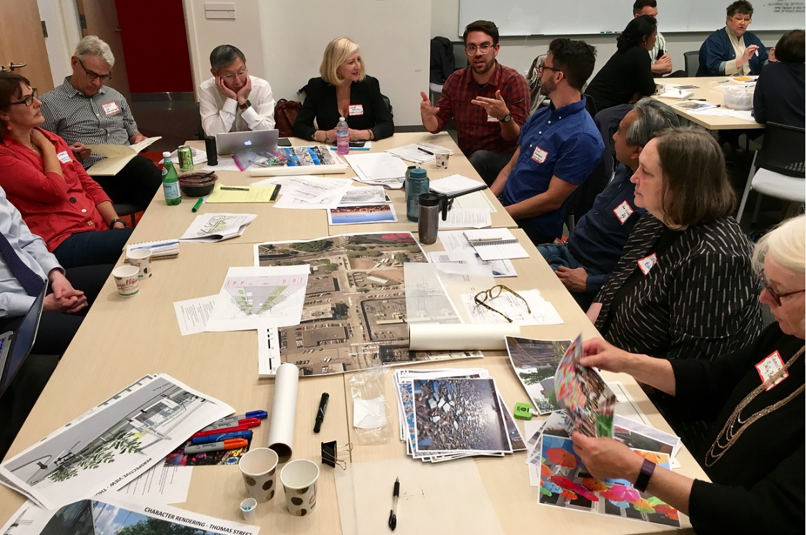 Image showing participants around the table with drawings and plan sets in discussion during the charrette.