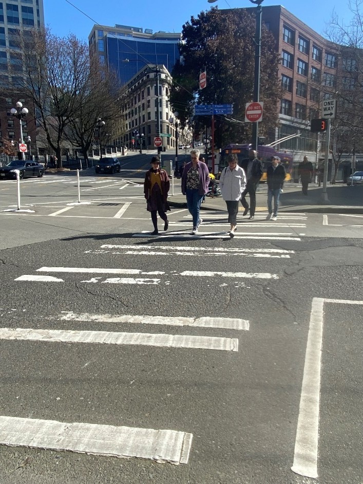 A photo of the current crosswalk at 3rd and Yesler, with temporary paint and flex posts which will be narrowed using installed curb bulbs