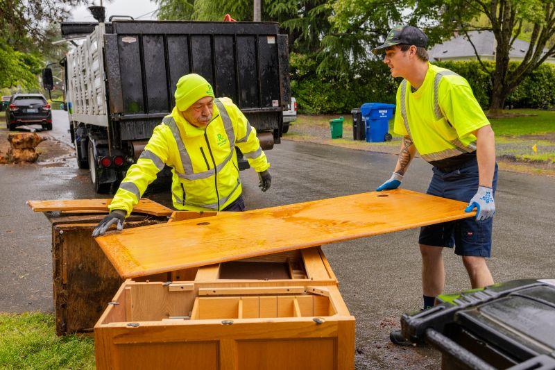 Workers cleaning up extra waste on a residential street.