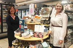 Two people standing in front of the Refugee Artisan Initiative’s display