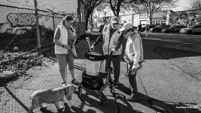 Three neighbors and a dog talking while cleaning up. Photo courtesy Erik Bell.