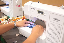 SHA Yesler Terrace workshop participant using a sewing machine to upcycle unwanted fabric waste