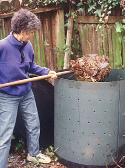 Photo of woman adding leaves to compost container